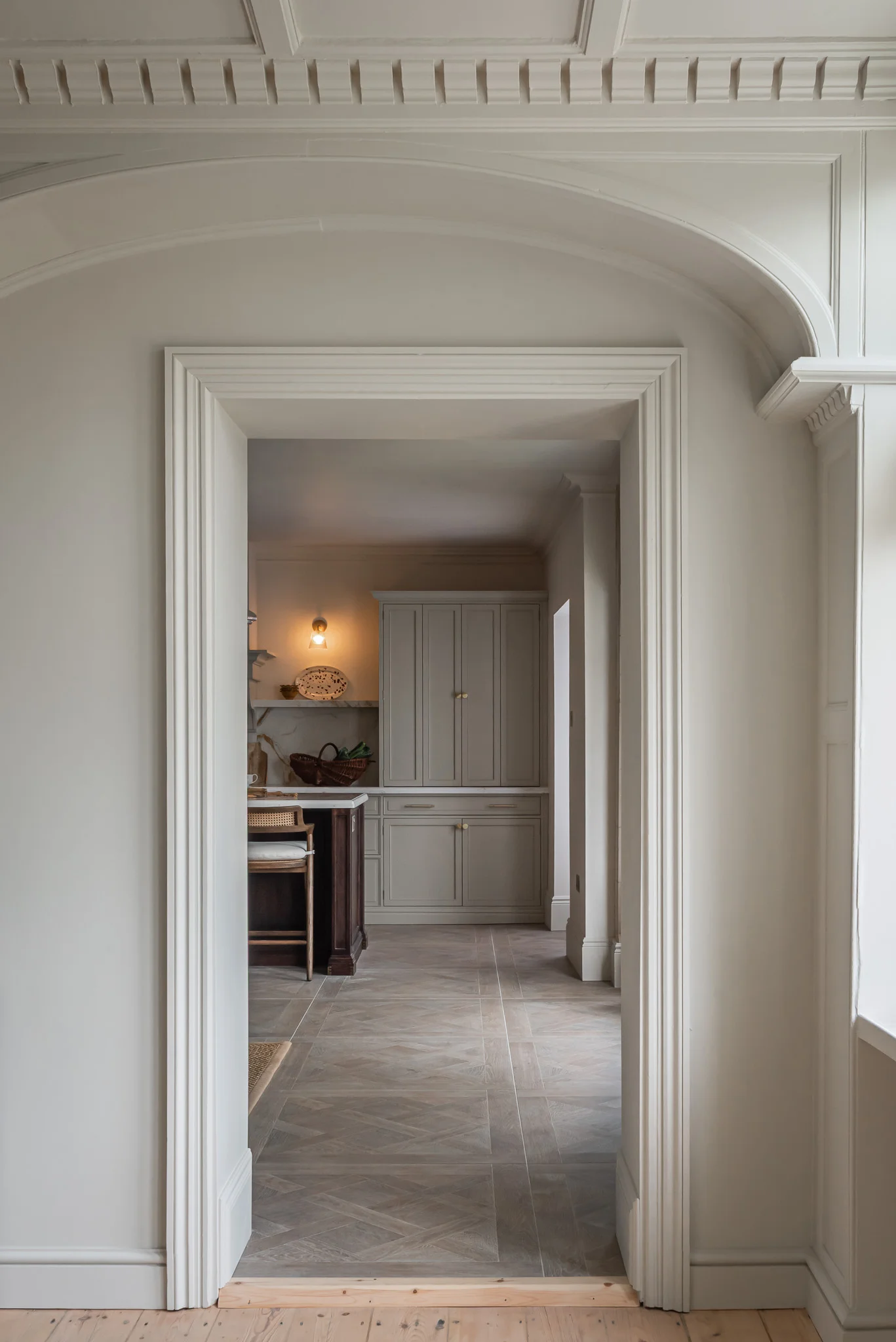 Broken-plan kitchen by The White Kitchen Company, with a tall run of hand-painted in-frame cabinetry separating the cooking area from the dining zone beyond.