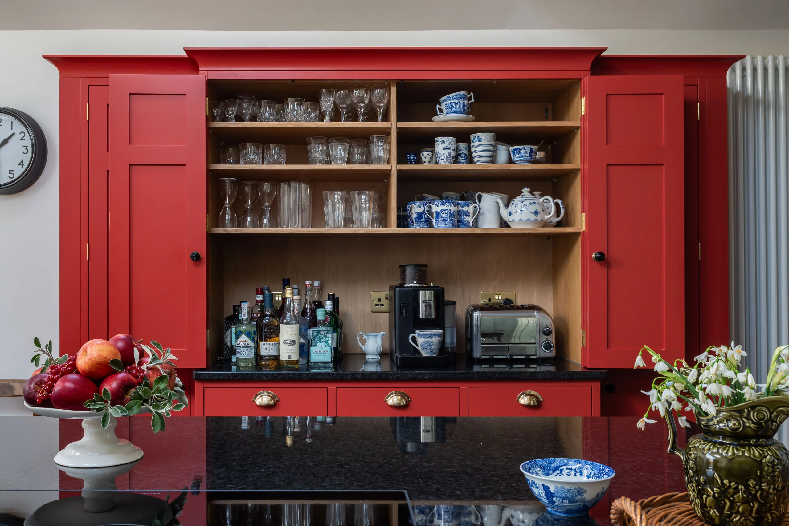 Open red in-frame breakfront cupboard at Grantchester Revival showing timber interiors and brass butt hinges